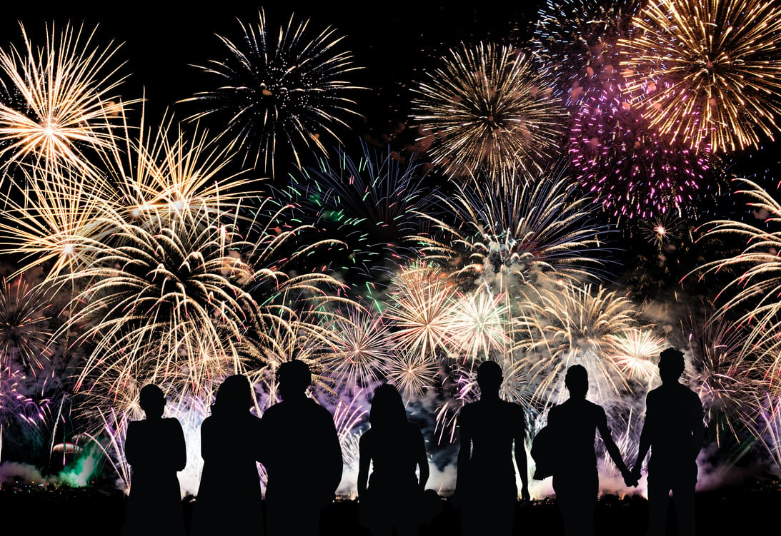 Group of people watch colorful holiday fireworks